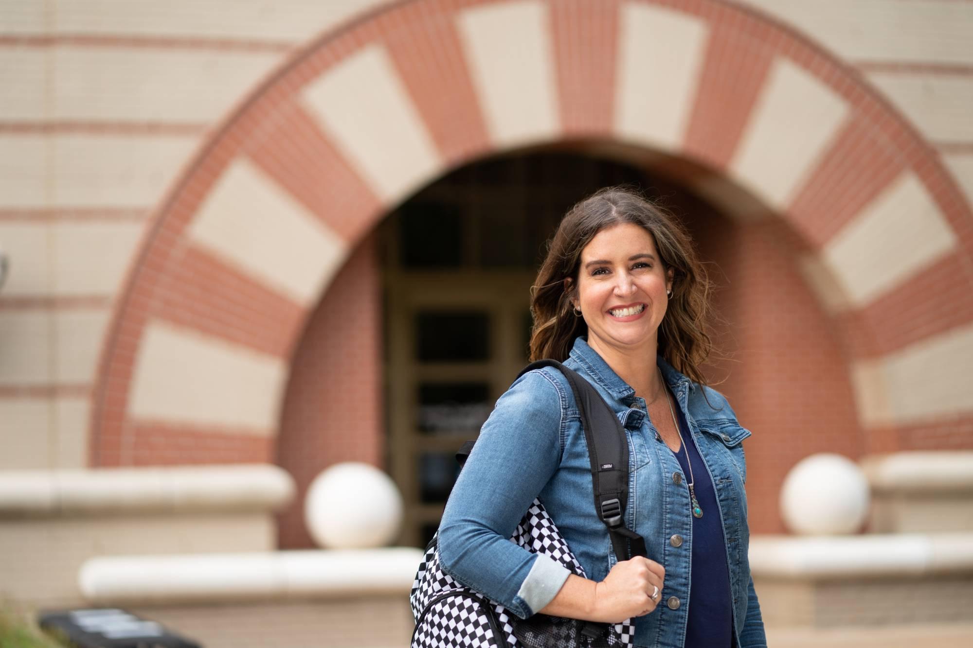 Woman standing in front of building with checkered purse over her shoulder